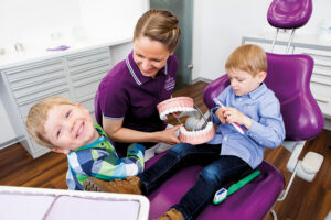 Gesunde Kinderzähne. Frau Dr. Köhler zusammen mit Kindern im Behandlungsraum.