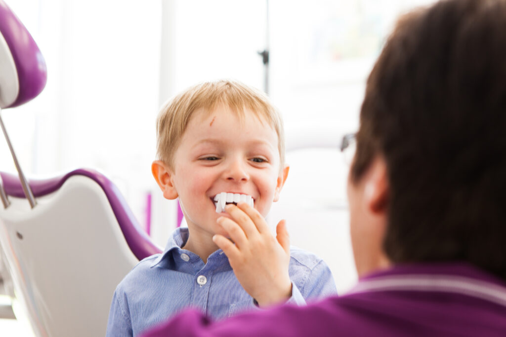 Innovative Behandlungsmöglichkeiten für Kinder. Eine Helferin hält einem Jungen ein kleines Gebiss vor den Mund.